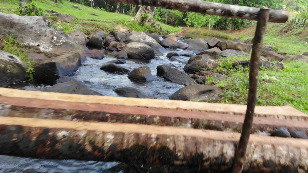Rocky creek rapids with a wooden plank in the foreground